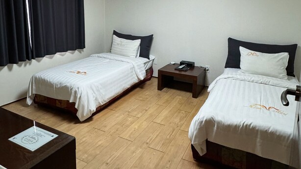 A hotel room with two beds, a desk, a nightstand, and a ceiling light. - High Valley Hotel (Jeongseon)