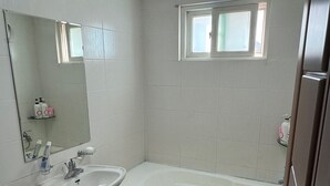 A bathroom with a toilet, sink, and bathtub. - High Valley Hotel (Jeongseon)