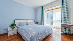 Ein Schlafzimmer mit einem Bett, einem Nachttisch, einer Kommode, einem Fenster mit Vorhängen und einer Pflanze.