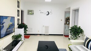 Ein modernes Wohnzimmer mit Flachbildfernseher, einem schwarzen Couchtisch, einer Couch und einem großen Fenster.