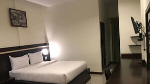 Quarto de hotel com cama, mesa de cabeceira e espelho.