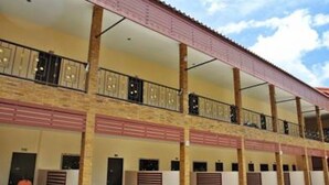 A multi-story hotel with balconies, a covered walkway, and a row of rooms with shutters.