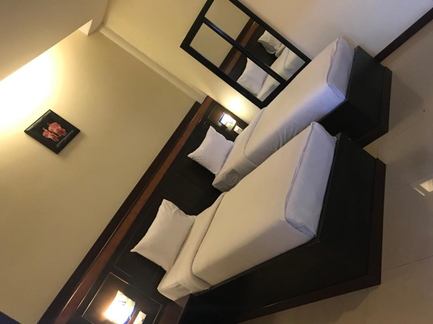 Una habitación de hotel moderna con una cama grande, un espejo y un cuadro en la pared.
