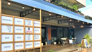 A restaurant with outdoor seating, a sign indicating it's open, and various amenities listed on a board. - AIEN Coffee and hostel (Chatan)
