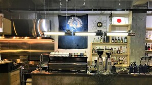 A bar area with a coffee machine, shelves with bottles, and a potted plant. - AIEN Coffee and hostel (Chatan)