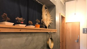 A room with a wooden shelf holding various potted plants and a round mirror. - AIEN Coffee and hostel (Chatan)