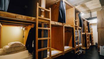 A dormitory room with bunk beds, wooden furniture, and a small desk.