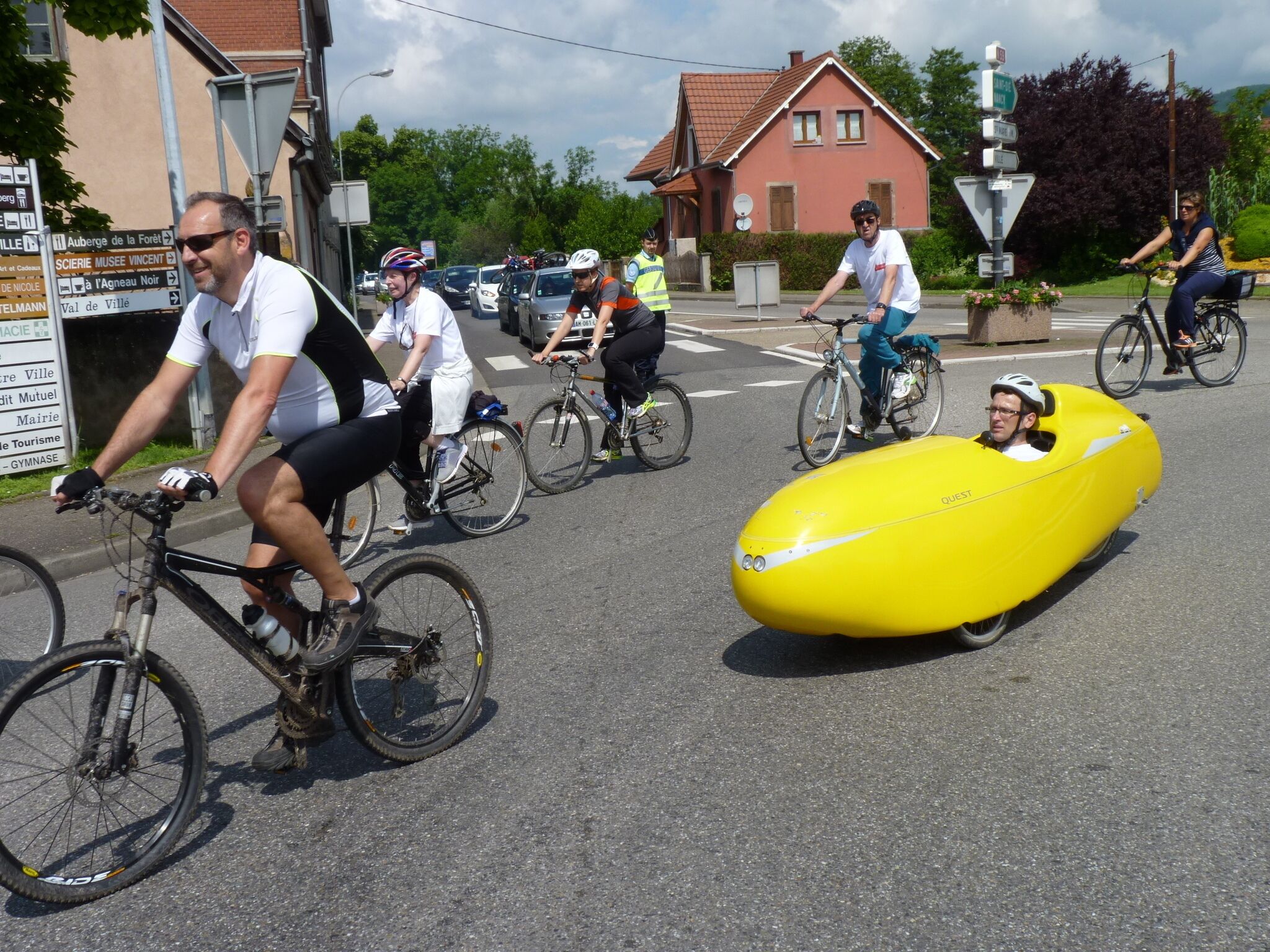 A street scene with cyclists, including one in a yellow balloon-like object.