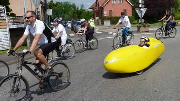 A street scene with cyclists, including one in a yellow balloon-like object.