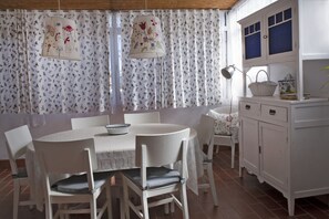A dining area with a round table, white chairs, and a white cabinet with blue-tinted windows. - Casa Albéitar, easy Parking, Wifi, Ronda (Ronda)