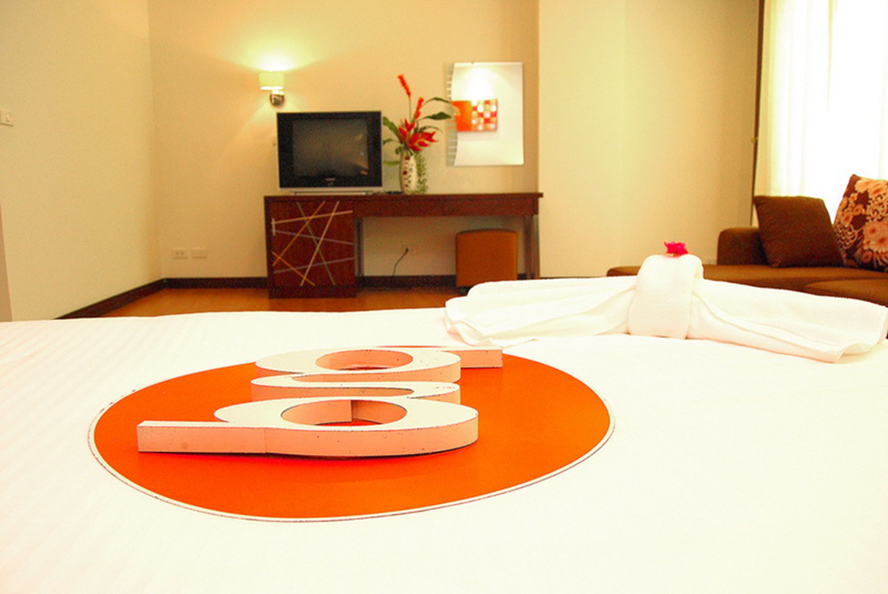 Een hotelkamer met een bed, een bureau met een televisie, een stoel en een bank.
