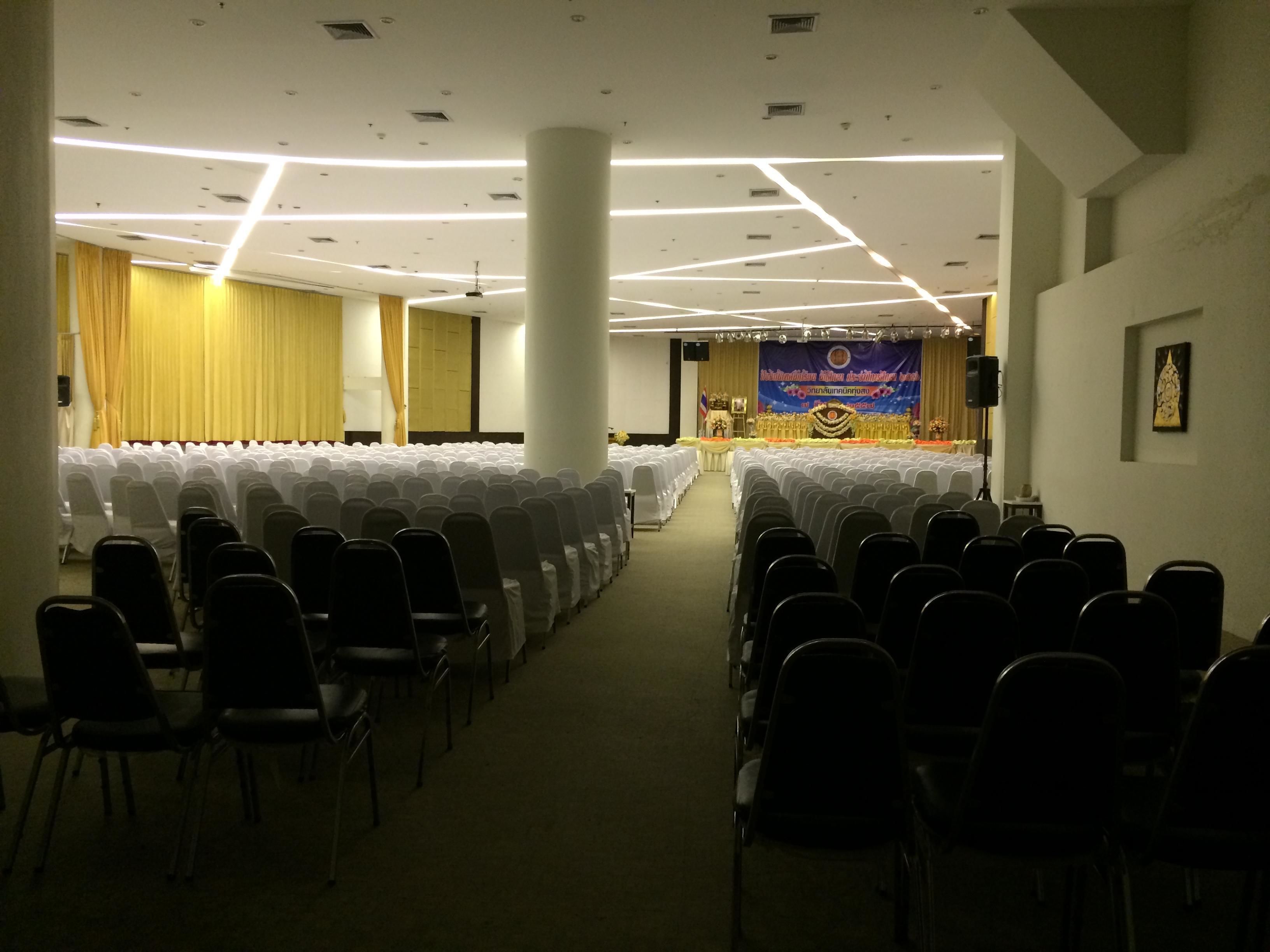A conference room with rows of chairs, a stage with a banner, and a large pillar.