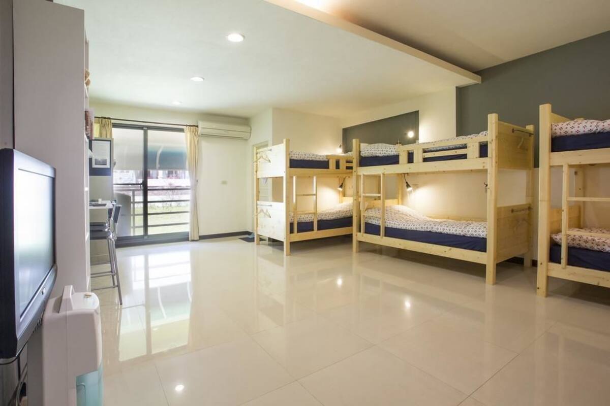 Una habitación con literas, televisión y puerta corrediza que da a un balcón.