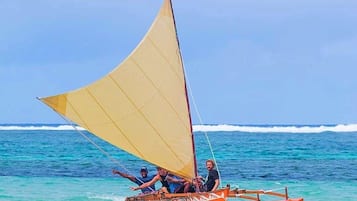 A traditional sailboat with passengers on a clear day at the ocean.
