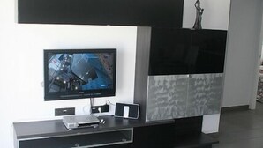 Una sala de estar moderna con un televisor de pantalla plana, una mesa de centro de vidrio y un mueble blanco y negro de diseño minimalista.