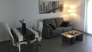 Una sala moderna con una mesa de comedor, sofá y un cuadro de un paisaje urbano.