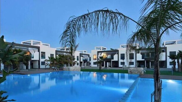 Un hotel moderno con piscina, palmeras y arquitectura contemporánea.