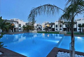 Un hotel moderno con piscina, palmeras y arquitectura contemporánea.