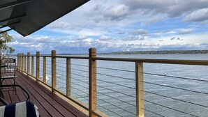 Une terrasse en bois avec une rambarde donnant sur une étendue d’eau, une table et des chaises.