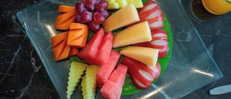 A fruit platter on a glass plate with a marble countertop.
