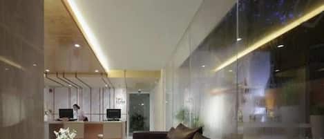 A modern lobby with a reception desk, seating area, and large windows.