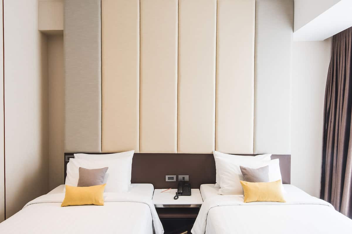 A hotel room with two beds, a nightstand, and a telephone.