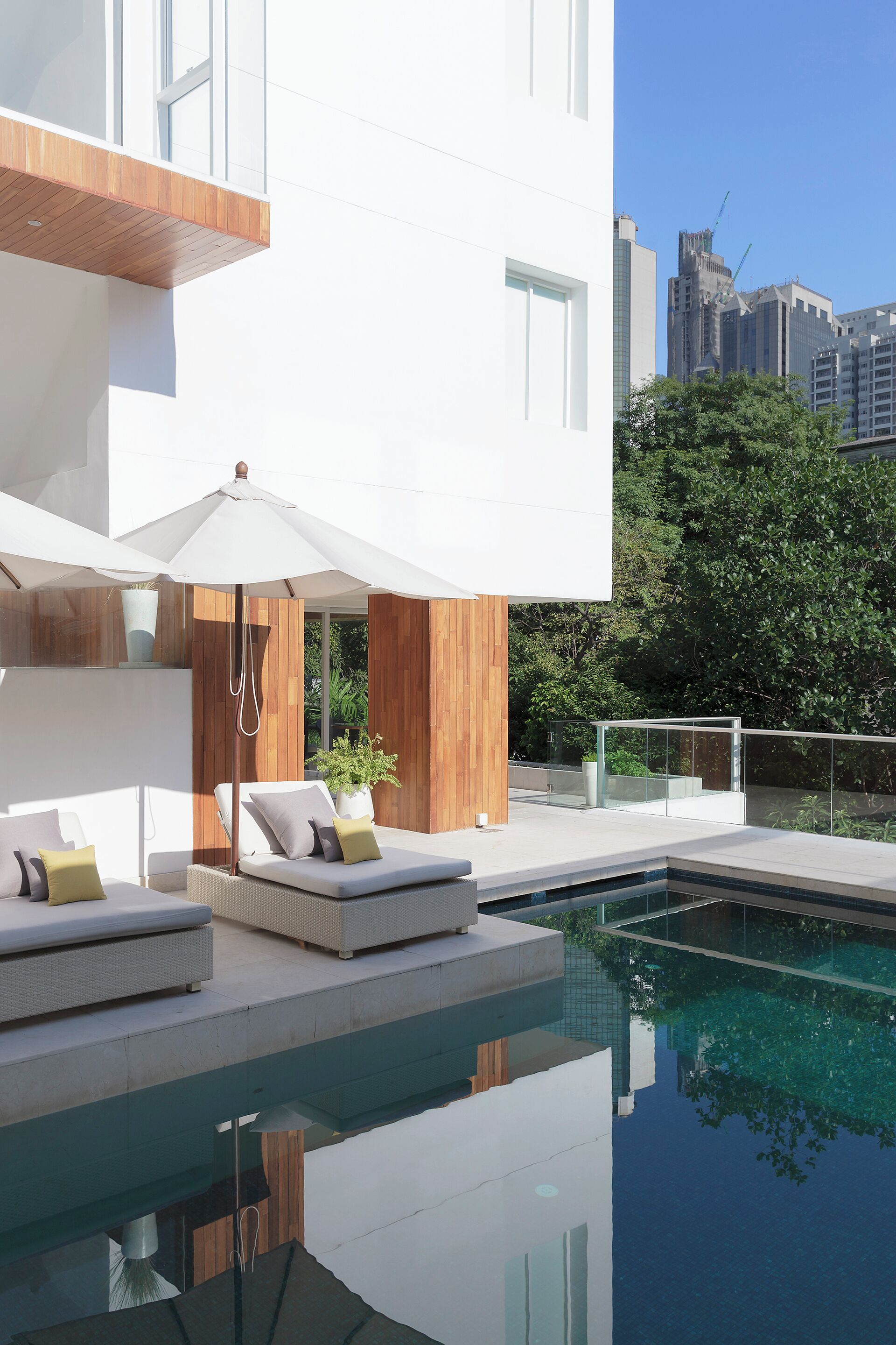 A modern outdoor pool area with lounge chairs and a glass balustrade.