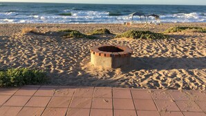 Uma praia com lareira, cadeiras de praia e vista para o oceano.
