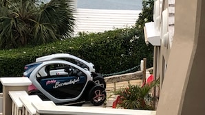 Un coche aparcado en un balcón con vistas a una masa de agua, el mar y colinas.
