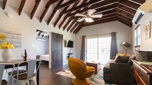 Amplia sala de estar con techo de madera, comedor con mesa y sillas, una moderna silla amarilla y un sofá.
