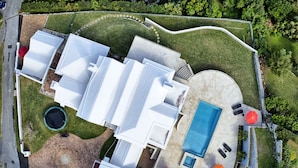 Vista aérea de una propiedad con piscina, mobiliario exterior y una estructura de ladrillo.