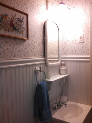 Une salle de bain avec un lavabo blanc, un miroir et un porte-serviettes.