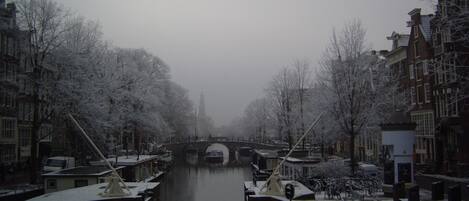 Un canal flanqueado por árboles y edificios cubiertos de nieve.