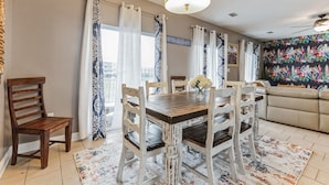 A dining area with a wooden table and chairs, a chandelier, and a colorful wall mural.