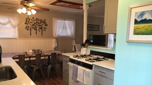 A compact kitchen with a gas stove, oven, and a dining area with a table and chairs. - Asheville Home - Walk To Everything! (Asheville)