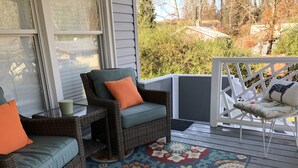 A covered porch with wicker furniture, a colorful rug, and a view of the surrounding area. - Asheville Home - Walk To Everything! (Asheville)