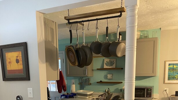 A kitchen with a bar area, two bar stools, hanging pots, a microwave, and a sink. - Asheville Home - Walk To Everything! (Asheville)