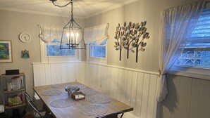A dining area with a wooden table, four chairs, a chandelier, and decorative wall art. - Asheville Home - Walk To Everything! (Asheville)