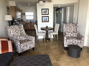 Een woonkamer met gestreept fauteuils, een ronde tafel en een bank.