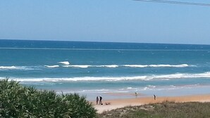 Una playa con gente caminando por la orilla y una vista despejada del océano.
