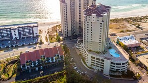 A high-rise hotel with a rooftop pool, adjacent parking, and a beach view. - BEACHFRONT GRAND PANAMA, 1st FLR DIRECT TO BEACH, PET-FRIENDLY. NEXT TO TIKI BAR (Panama City Beach)