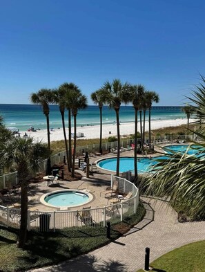 A resort with two swimming pools, a beach, and palm trees. - BEACHFRONT GRAND PANAMA, 1st FLR DIRECT TO BEACH, PET-FRIENDLY. NEXT TO TIKI BAR (Panama City Beach)