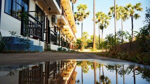 Un hotel con una piscina reflectante, palmeras y cielo despejado.