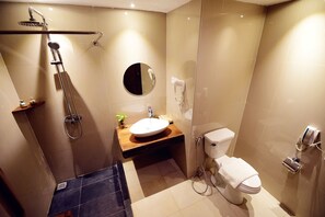 Uma casa de banho moderna com chuveiro, sanita e lavatório.