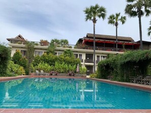 Um hotel com piscina, rodeado por vegetação exuberante e palmeiras.