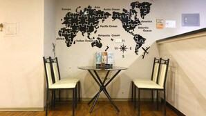 Una pared con un rompecabezas de mapa mundial, dos sillas, una mesa y un globo terráqueo pequeño.