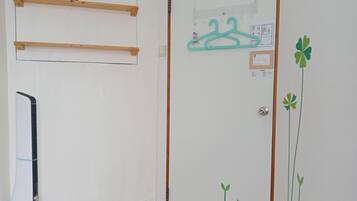 A room with a white door, wooden shelves, a wall-mounted drying rack, and a radiator.