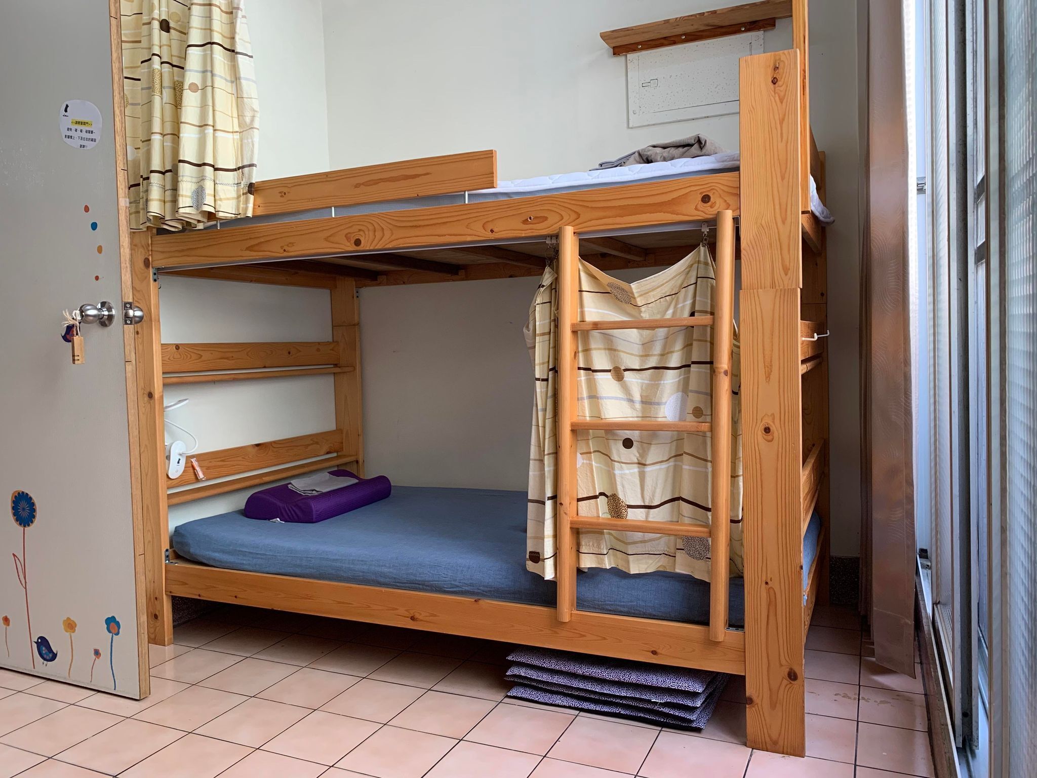 A bunk bed with a ladder, a small shelf, and a door with a lock.