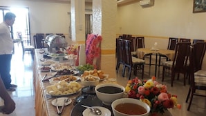 A buffet setup with various dishes and a floral centerpiece. - Nhat Ha Hotel (Can Tho)