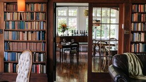 A library with bookshelves, a dining area, and a leather couch. - Wallingford Homestead (Wallingford)